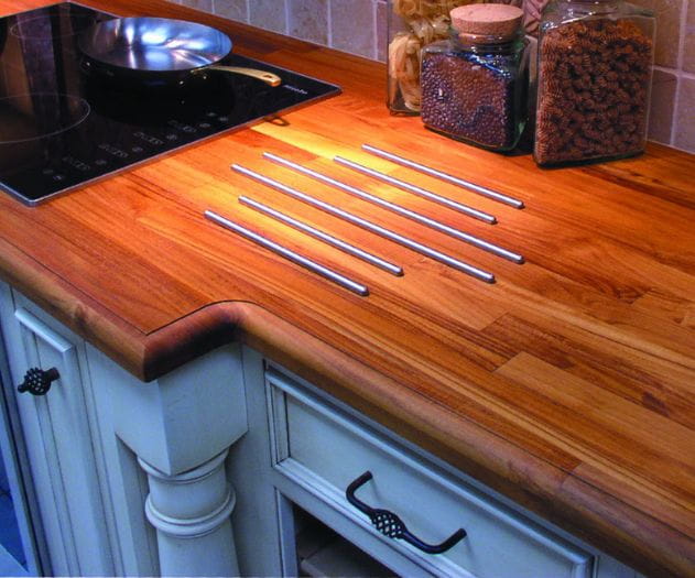 Kitchen countertop with wooden surface, stovetop, pan, and storage jars containing various items such as spices.