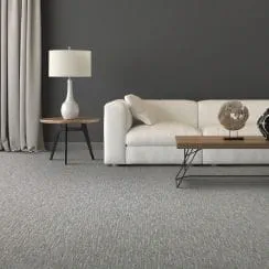 Modern living room with gray carpet, white sofa, and wooden coffee table featuring minimalist decor.