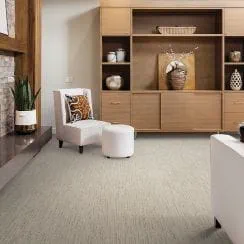 A view of a modern living room with a chair, ottoman, and wooden shelving displaying decorative items.