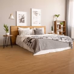A modern minimalist bedroom with a wooden headboard, decorative bedding, and green plants.