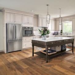 Modern kitchen with a central wooden island, hardwood flooring, and stainless steel appliances.