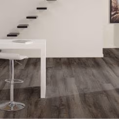 Minimalist room featuring dark wood plank flooring, a white desk with chair, and a staircase.