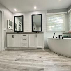 Modern bathroom with a double vanity, freestanding bathtub, and natural wood-like tile flooring.
