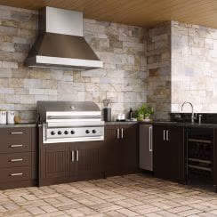 Outdoor kitchen with stone tiles, a barbecue grill, and dark cabinetry.