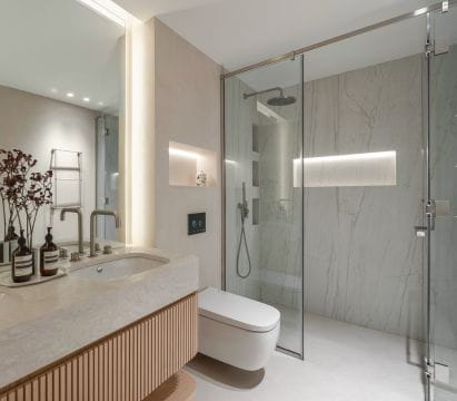 Modern bathroom showcasing a glass shower installation, marble countertop, and integrated lighting design.