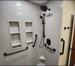 Bathroom shower area with safety rails and modern shower fixtures designed for accessibility.