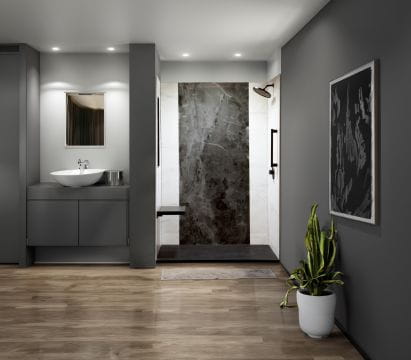 Modern bathroom interior with gray walls, vanity with a white sink, polished stone shower area, and houseplant accent.