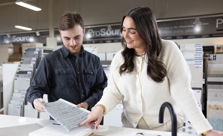 Two individuals in a showroom reviewing design materials on a counter.