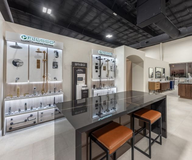 Interior view of a luxurious plumbing showroom displaying modern fixtures and designs with a central table and stools.