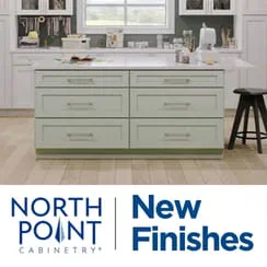 A kitchen display featuring NorthPoint Cabinetry's new finishes with a central island and cabinetry in a showroom.