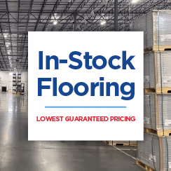 Warehouse interior with pallets of flooring and a banner for guaranteed lowest pricing in in-stock flooring.