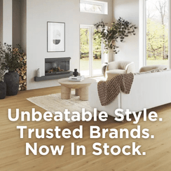 A modern living room interior featuring a white sofa, wooden flooring, and a fireplace with greenery. Overlaid text reads, 'Unbeatable Style. Trusted Brands. Now In Stock.'