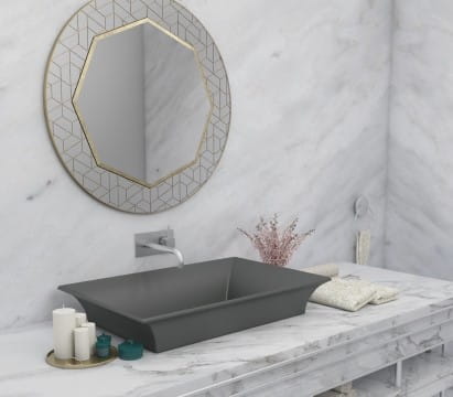 Gray bathroom sink shown with circular mirror overhead