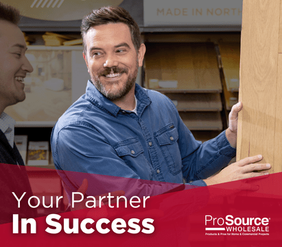 Individual holding a wooden flooring sample in a store, with ProSource Wholesale branding and text 'Your Partner In Success'.