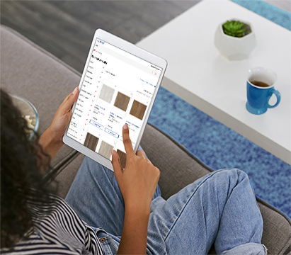 Person sitting on a couch holding a tablet and browsing an online store displaying product options.