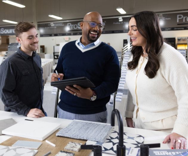 Three individuals discussing design samples in a modern showroom.
